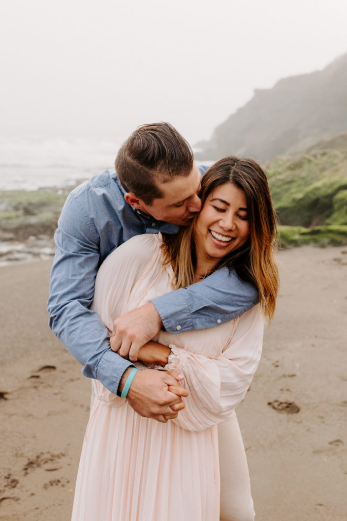 man kissing woman on cheek on beach, Marin Headlands Engagement Photos, Bay Area Engagement Photos, Bay Area Engagement Photo Locations, Engagement Photo Outfits, Bay Area Beach Engagement Photos, Dog Friendly Bay Area Beaches, Best Locations for Bay Area Engagement Photos, San Francisco Engagement Photos, What to Wear for Engagement Photos, Engagement Photos with dogs, Rachel Christopherson Photography LLC