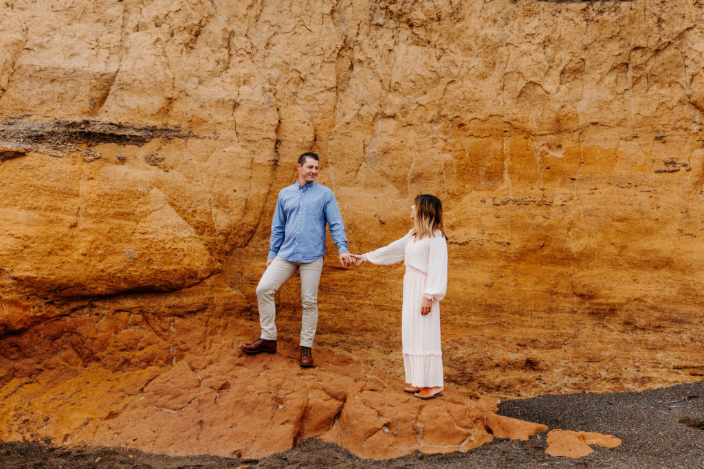 couple holding hands on orange rocks, Marin Headlands Engagement Photos, Bay Area Engagement Photos, Bay Area Engagement Photo Locations, Engagement Photo Outfits, Bay Area Beach Engagement Photos, Dog Friendly Bay Area Beaches, Best Locations for Bay Area Engagement Photos, San Francisco Engagement Photos, What to Wear for Engagement Photos, Engagement Photos with dogs, Rachel Christopherson Photography LLC