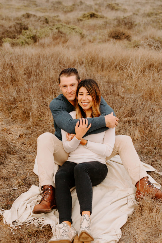 couple sitting on blanket in grass, Marin Headlands Engagement Photos, Bay Area Engagement Photos, Bay Area Engagement Photo Locations, Engagement Photo Outfits, Coastal Bay Area Engagement Photos, Dog Friendly Bay Area Beaches, Best Locations for Bay Area Engagement Photos, San Francisco Engagement Photos, What to Wear for Engagement Photos, Engagement Photos with dogs, Rachel Christopherson Photography LLC