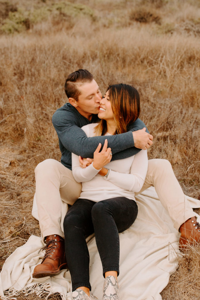 man kissing woman's cheek on blanket, Marin Headlands Engagement Photos, Bay Area Engagement Photos, Bay Area Engagement Photo Locations, Engagement Photo Outfits, Coastal Bay Area Engagement Photos, Dog Friendly Bay Area Beaches, Best Locations for Bay Area Engagement Photos, San Francisco Engagement Photos, What to Wear for Engagement Photos, Engagement Photos with dogs, Rachel Christopherson Photography LLC