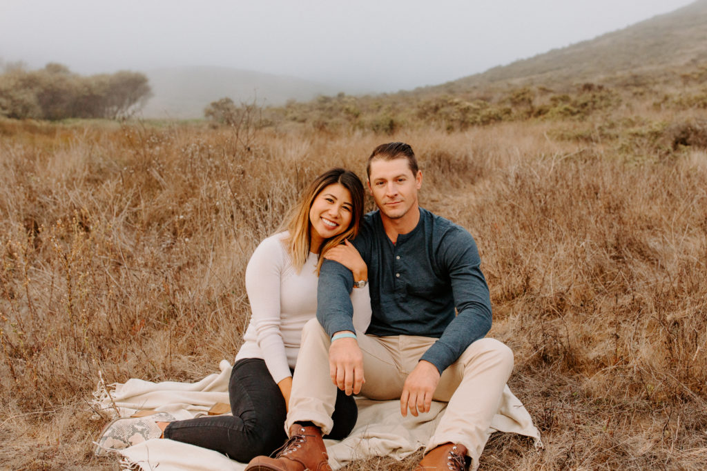 couple sitting in field on blanket, Marin Headlands Engagement Photos, Bay Area Engagement Photos, Bay Area Engagement Photo Locations, Engagement Photo Outfits, Coastal Bay Area Engagement Photos, Dog Friendly Bay Area Beaches, Best Locations for Bay Area Engagement Photos, San Francisco Engagement Photos, What to Wear for Engagement Photos, Engagement Photos with dogs, Rachel Christopherson Photography LLC
