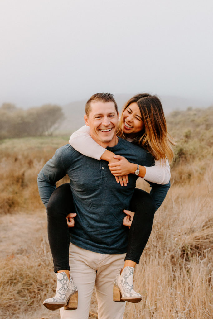 couple laughing in piggy back, Marin Headlands Engagement Photos, Bay Area Engagement Photos, Bay Area Engagement Photo Locations, Engagement Photo Outfits, Coastal Bay Area Engagement Photos, Dog Friendly Bay Area Beaches, Best Locations for Bay Area Engagement Photos, San Francisco Engagement Photos, What to Wear for Engagement Photos, Engagement Photos with dogs, Rachel Christopherson Photography LLC