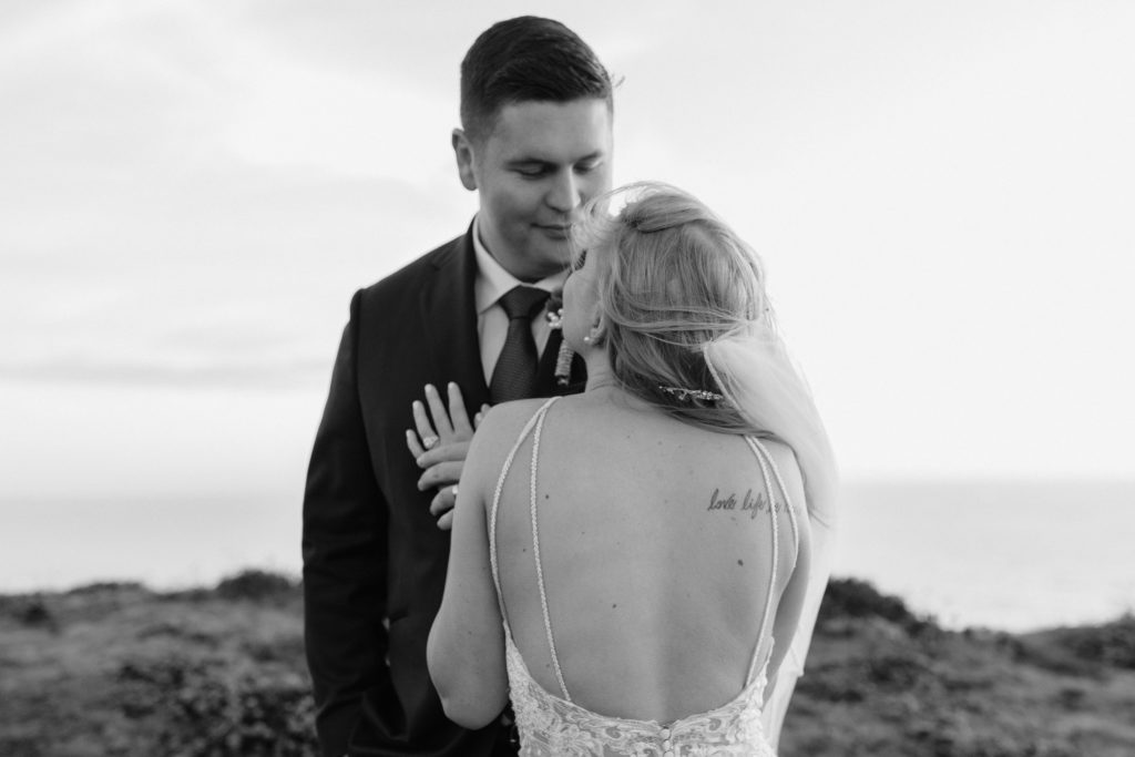 black and white wedding photo at ocean, bride and groom kiss on cliff, elopement dress, Mendocino elopement, mendocino wedding, christmas elopement, best places to elope in california, norcal elopement, northern california elopement, elopement inspo, california coast elopement, mendocino california elopement, Rachel Christopherson Photography 