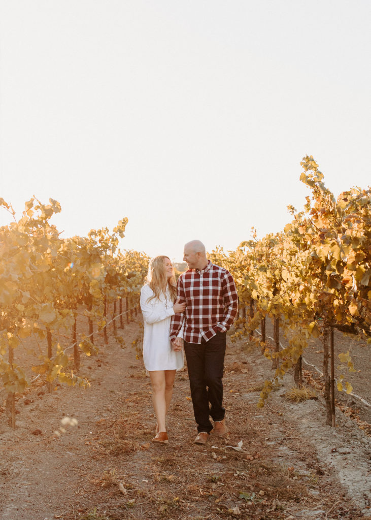 couple walking through golden vineyard, vineyard engagement photos, Sacramento engagement photos, sacramento engagement, sacramento engagement photographer sacramento engagement photo locations, sacramento wedding photographer, rachel christopherson photography, engagement photo outfit inspo