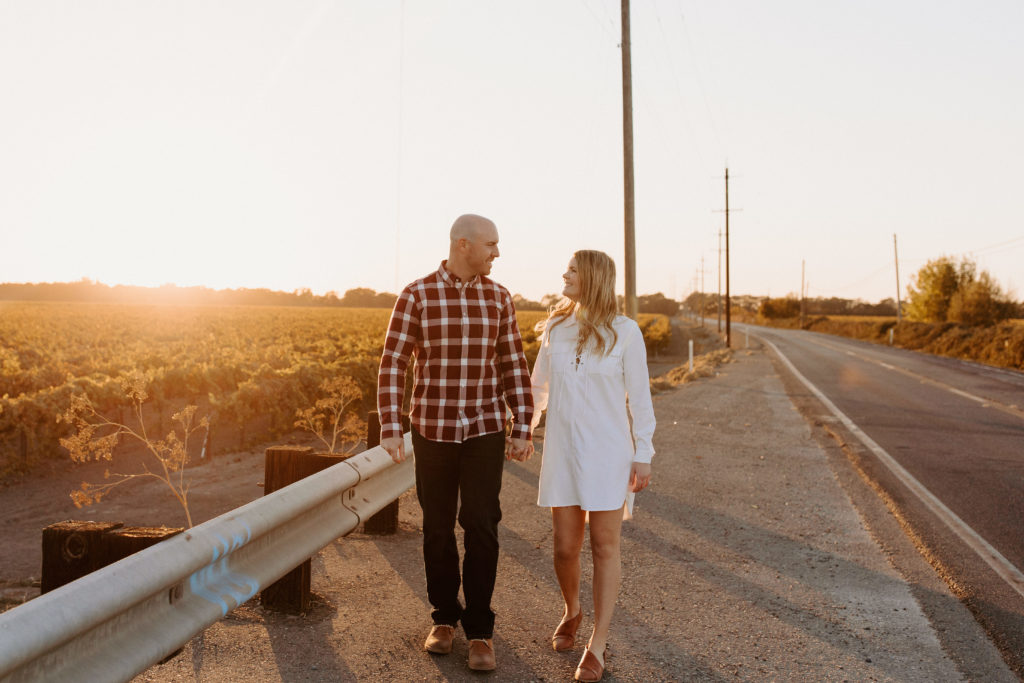 couple walking on country road during sunset, vineyard engagement photos, Sacramento engagement photos, sacramento engagement, sacramento engagement photographer sacramento engagement photo locations, sacramento wedding photographer, rachel christopherson photography, engagement photo outfit inspo