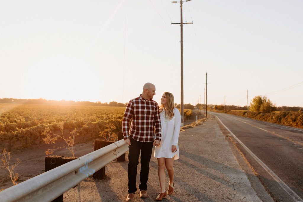 couple walking on country road during sunset, vineyard engagement photos, Sacramento engagement photos, sacramento engagement, sacramento engagement photographer sacramento engagement photo locations, sacramento wedding photographer, rachel christopherson photography, engagement photo outfit inspo