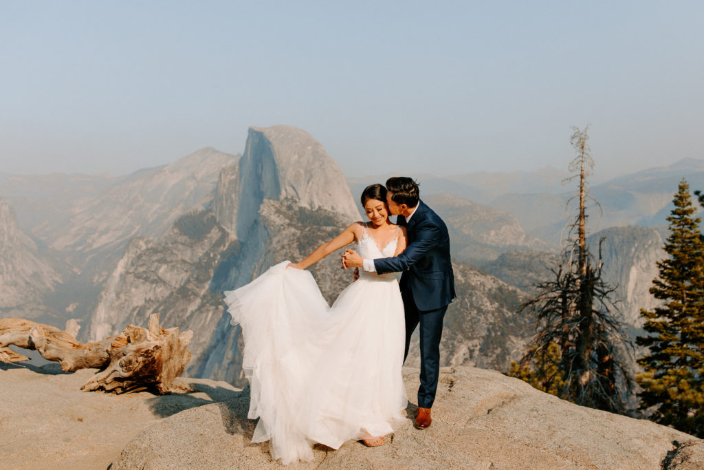groom kissing bride while bride swings dress at Glacier Point, Yosemite Elopement, Glacier Point Elopement, best places to elope in california, northern california elopement, Rachel Christopherson Photography