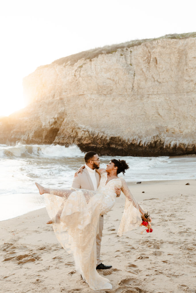 Groom lifting bride on beach, Santa cruz wedding, santa cruz elopement, santa cruz wedding photographer, santa cruz elopement photographer, big sur elopement, boho beach bride, california boho elopement, boho wedding dress, best places to elope in California, California elopement, California beach elopement, boho bride inspo, Rachel Christopherson Photography