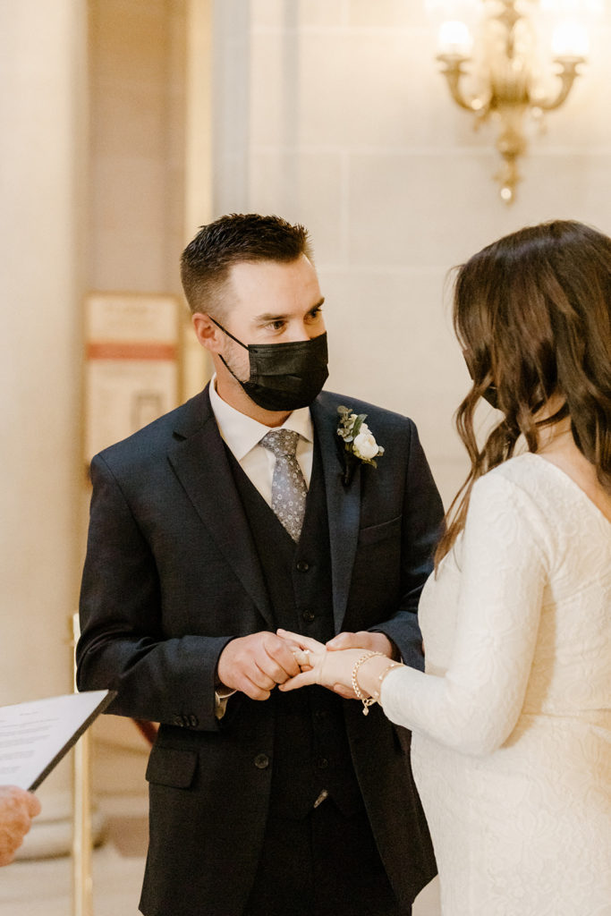 Rachel Christopherson Photographer-SF, San Francisco city hall elopement, san francisco wedding, wedding ceremony, groom putting wedding band on bride, dark gray grooms suit, ivory wedding dress