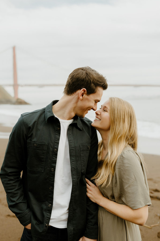 Rachel Christopherson Photography - Engaged couple smiling at each other in front of golden gate bridge, kirby cove engagement photos