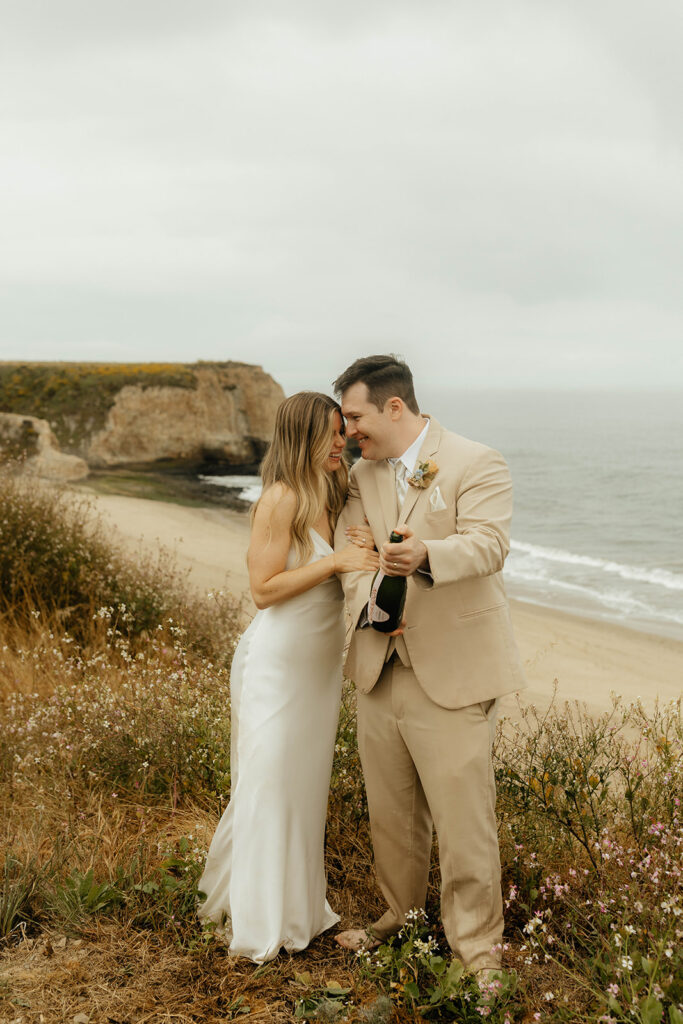 Bride and groom popping champagne on the beach