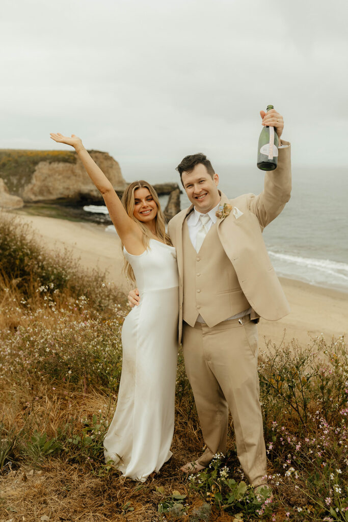 Bride and groom popping champagne on the beach