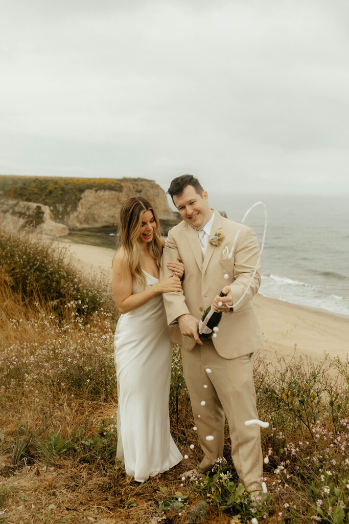 Bride and groom popping champagne on the beach
