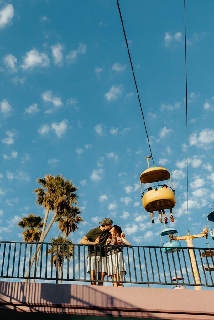 Couple kissing in front of boardwalk ride