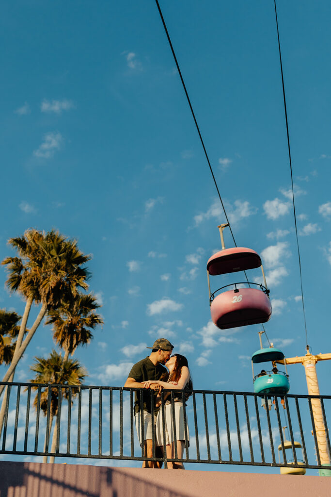 Couple kissing in front of boardwalk rides