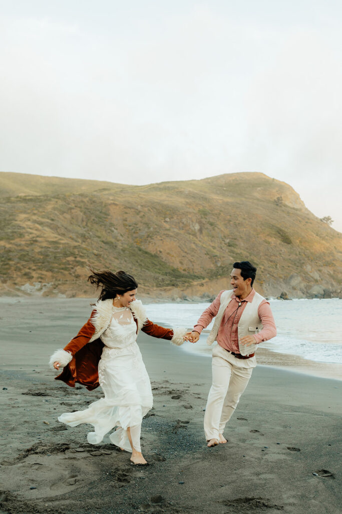 Bride and groom running along Muir Beach