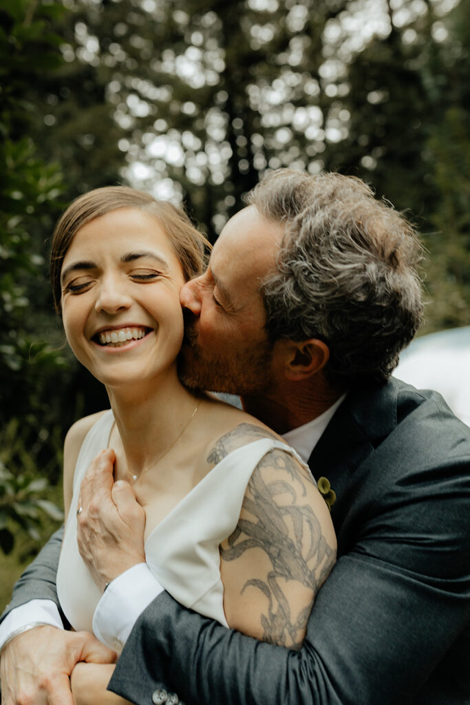 groom kissing the bride on the cheek 