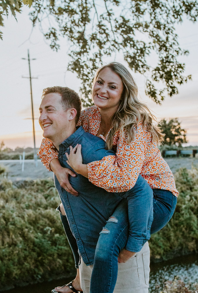 Sacramento River Engagement Session Northern California Weiner dog engagement shoot outfit inspo engagement photos with dog couples shoot posing golden hour sacramento river rachel christopherson photography piggy back laughter