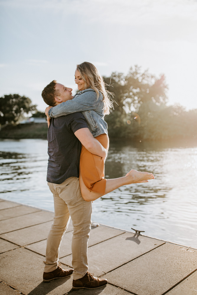 Sacramento River Engagement Session Northern California Weiner dog engagement shoot outfit inspo engagement photos with dog couples shoot posing golden hour sacramento river rachel christopherson photography lift up 
