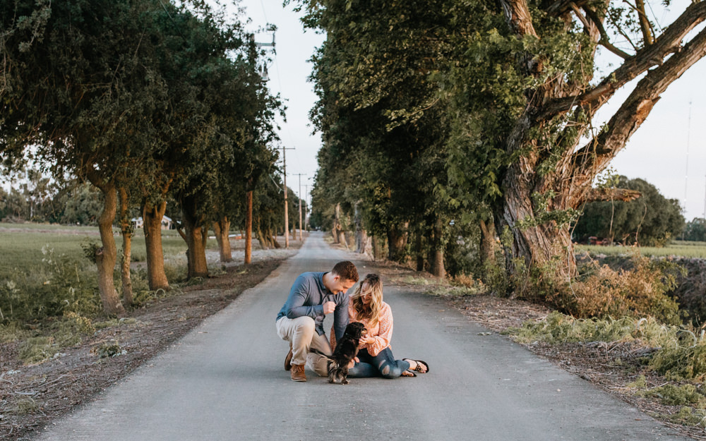 Sacramento River Engagement Session Northern California Weiner dog engagement shoot outfit inspo engagement photos with dog couples shoot posing golden hour sacramento river rachel christopherson photography tree lined street
