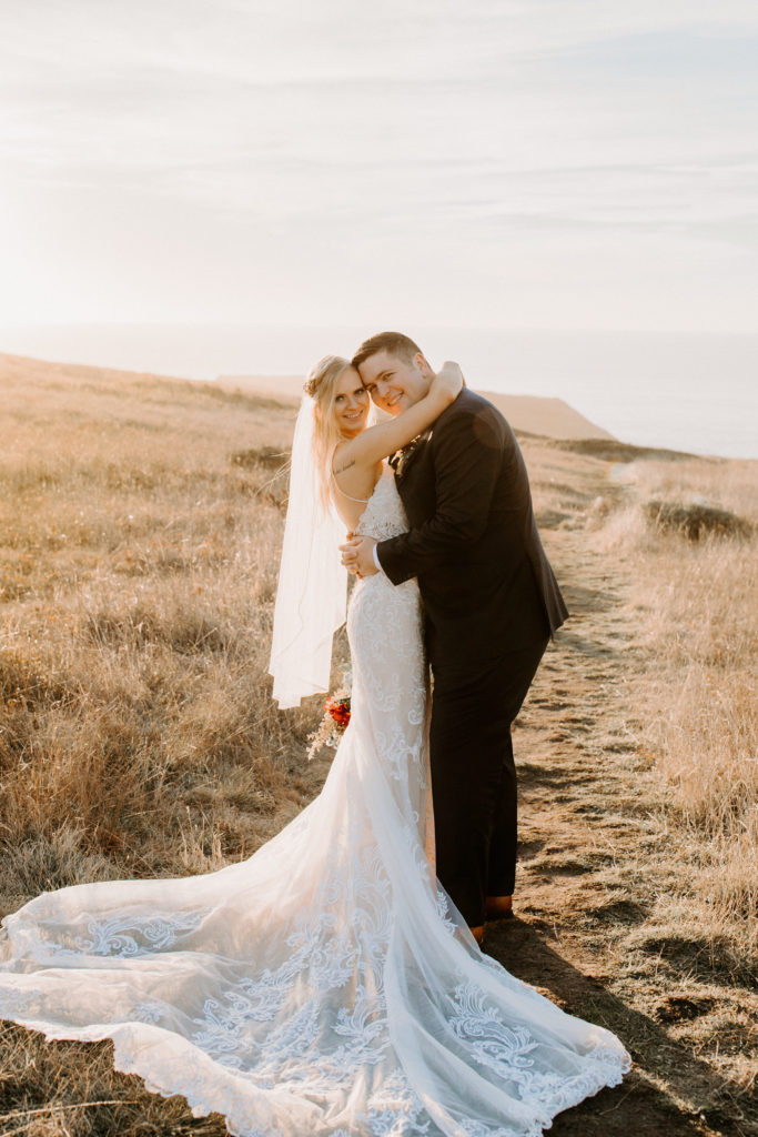 bride and groom smiling at camera in field, Mendocino elopement, mendocino wedding, christmas elopement, best places to elope in california, norcal elopement, northern california elopement, elopement inspo, california coast elopement, mendocino california elopement, Rachel Christopherson Photography 
