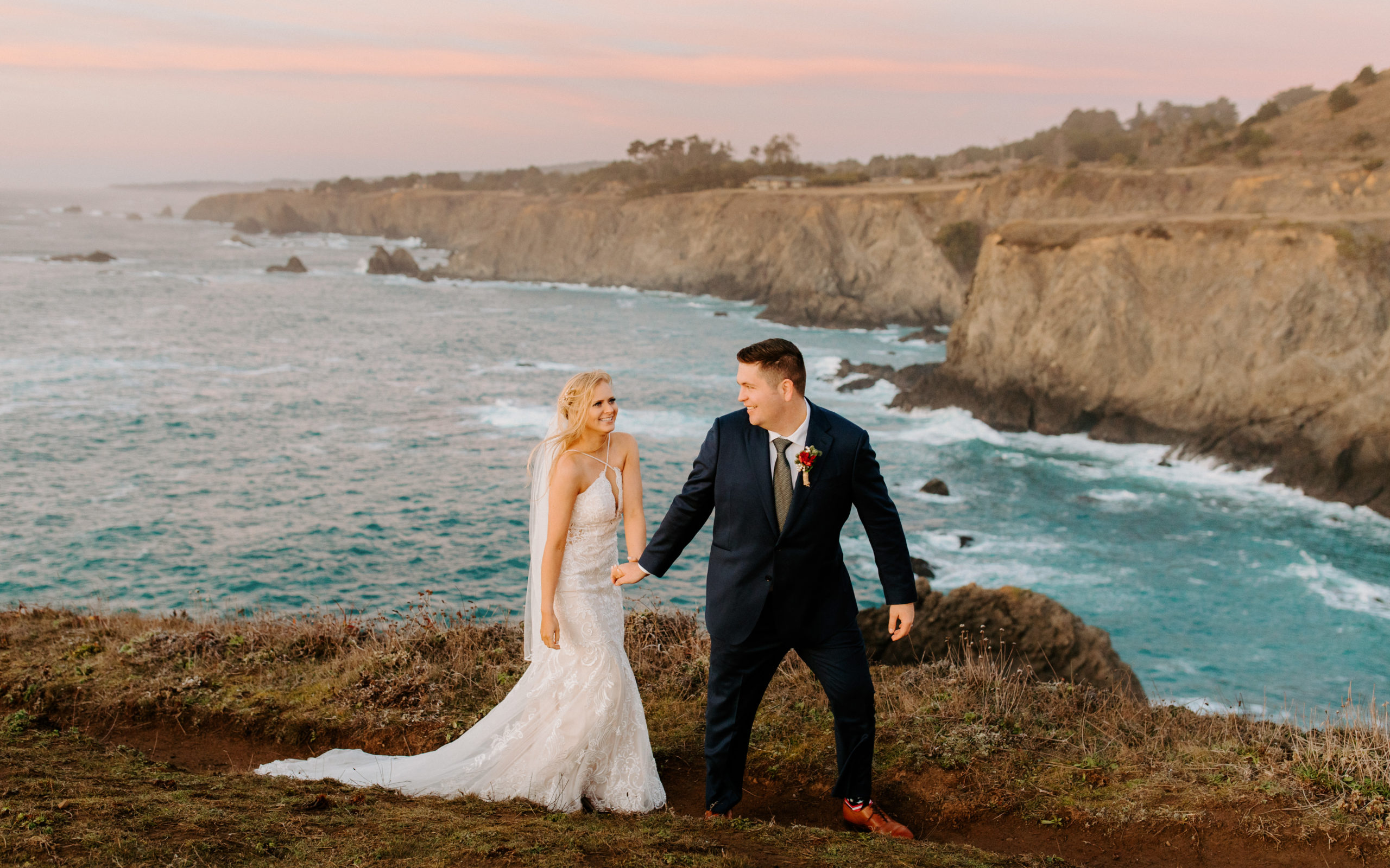 bride and groom walking at sunset on ocean cliff, bride and groom kiss on cliff, elopement dress, wedding dress train, Mendocino elopement, mendocino wedding, mendocino, mendocino elopement inspo, christmas elopement, best places to elope in california, norcal elopement, northern california elopement, elopement inspo, california coast elopement, mendocino elopement inspo, how to elope in mendocino, mendocino california elopement, Rachel Christopherson Photography