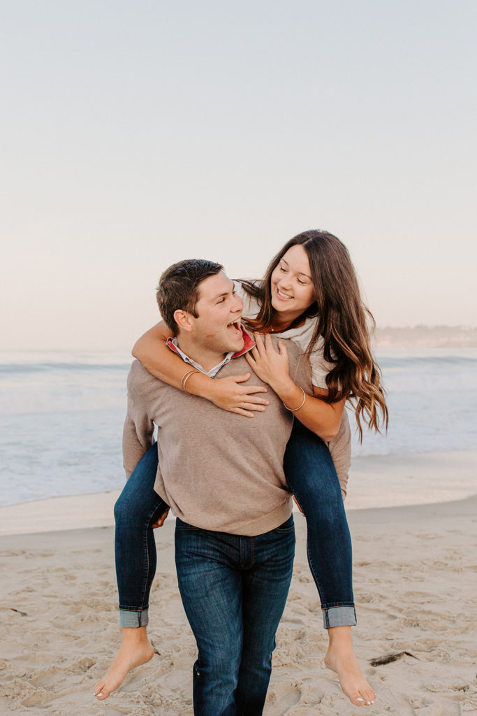 piggy back ride couple on beach, Carmel CA Engagement Photos, Monterey Engagement Photos, Monterey Engagement Photo Locations, Engagement Photo Outfits, California Beach Engagement Photos, Best Locations for Monterey Engagement Photos, What to Wear for Engagement Photos, Rachel Christopherson Photography LLC