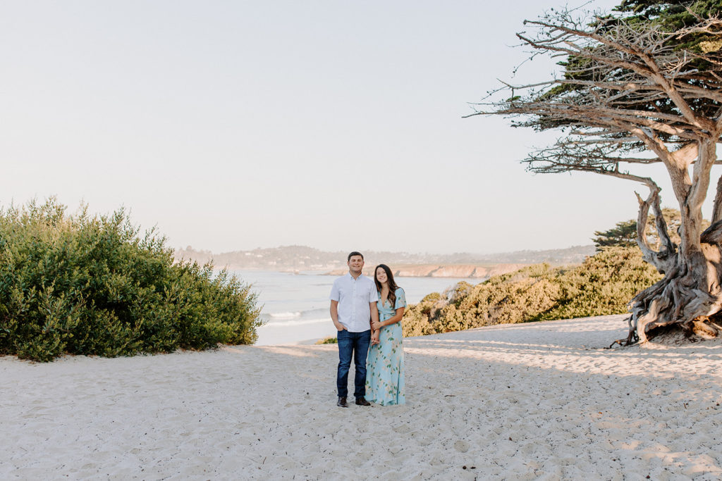 couple smiling at camera, man lifting woman playfully on beach, Carmel CA Engagement Photos, Monterey Engagement Photos, Monterey Engagement Photo Locations, Engagement Photo Outfits, California Beach Engagement Photos, Best Locations for Monterey Engagement Photos, What to Wear for Engagement Photos, Rachel Christopherson Photography LLC