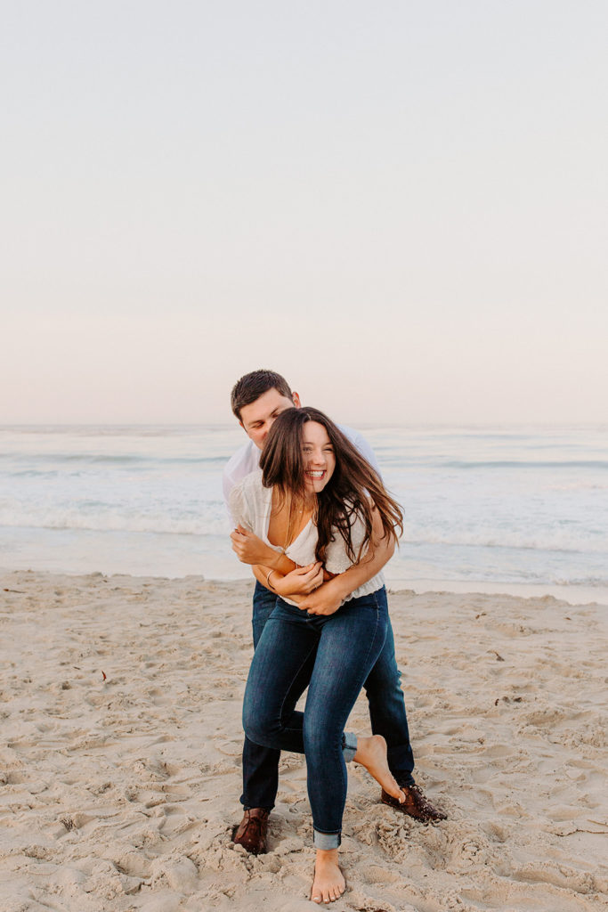 couple hugs from behind, Carmel CA Engagement Photos, Monterey Engagement Photos, Monterey Engagement Photo Locations, Engagement Photo Outfits, California Beach Engagement Photos, Best Locations for Monterey Engagement Photos, What to Wear for Engagement Photos, Rachel Christopherson Photography LLC