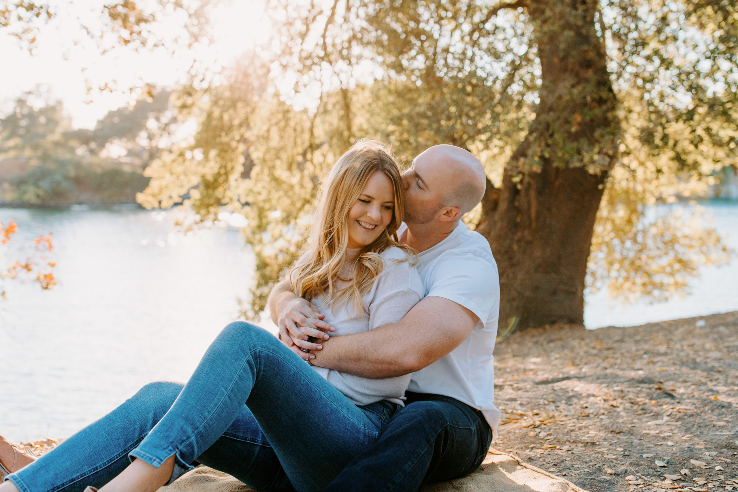 couple sitting under tree in front of river, Sacramento engagement photos, sacramento engagement, sacramento engagement photographer sacramento engagement photo locations, sacramento wedding photographer, rachel christopherson photography, engagement photo outfit inspo