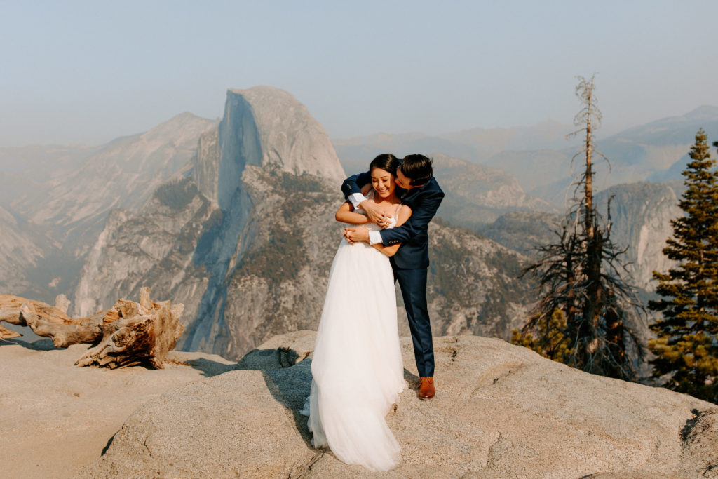 groom hugging bride from behind at Glacier Point, Yosemite Elopement, Glacier Point Elopement, best places to elope in california, northern california elopement, Rachel Christopherson Photography