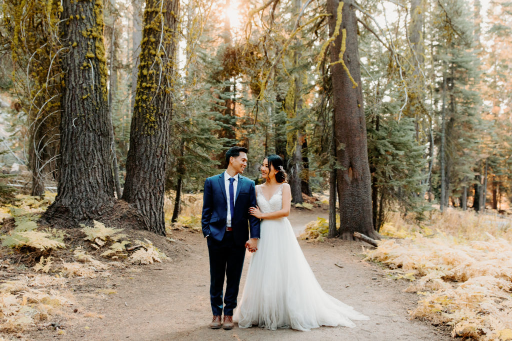 bride and groom walk in forest looking at each other, adventurous bride, wedding dress and hiking boots, Taft Point elopement, Yosemite Elopement, Glacier Point Elopement, best places to elope in california, northern california elopement, Rachel Christopherson Photography
