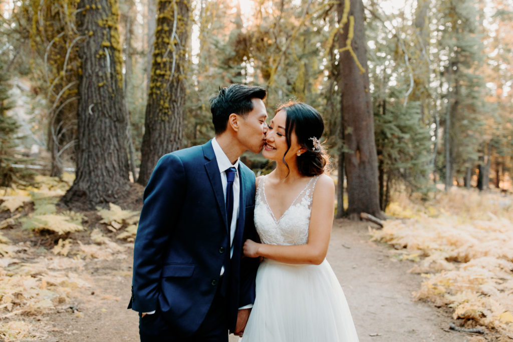 groom kisses bride on cheek in forest, adventurous bride, wedding dress and hiking boots, Taft Point elopement, Yosemite Elopement, Glacier Point Elopement, best places to elope in california, northern california elopement, Rachel Christopherson Photography