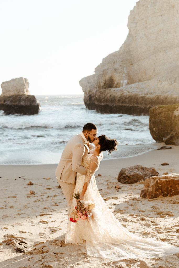 groom kissing bride while dipping her on the beach, Santa cruz wedding, santa cruz elopement, santa cruz wedding photographer, santa cruz elopement photographer, boho wedding dress, big sur elopement, boho beach bride, california boho elopement, best places to elope in California, California elopement, California beach elopement, boho bride inspo, Rachel Christopherson Photography