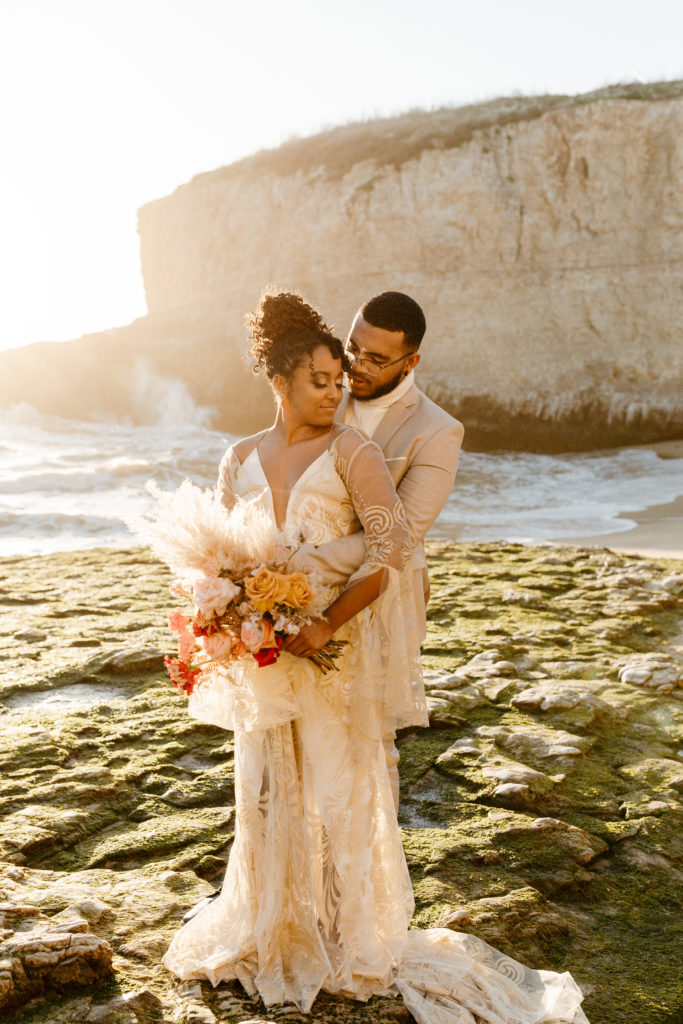 groom standing behind bride at beach, groom dipping bride for kiss at sunset, Santa cruz wedding, santa cruz elopement, santa cruz wedding photographer, santa cruz elopement photographer, big sur elopement, boho beach bride, california boho elopement, boho wedding dress, best places to elope in California, California elopement, California beach elopement, boho bride inspo, Rachel Christopherson Photography