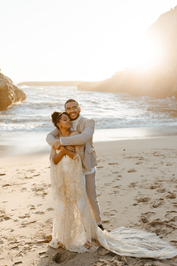 groom hugging bride from behind, Santa cruz wedding, santa cruz elopement, santa cruz wedding photographer, santa cruz elopement photographer, big sur elopement, boho beach bride, california boho elopement, boho wedding dress, best places to elope in California, California elopement, California beach elopement, boho bride inspo, Rachel Christopherson Photography