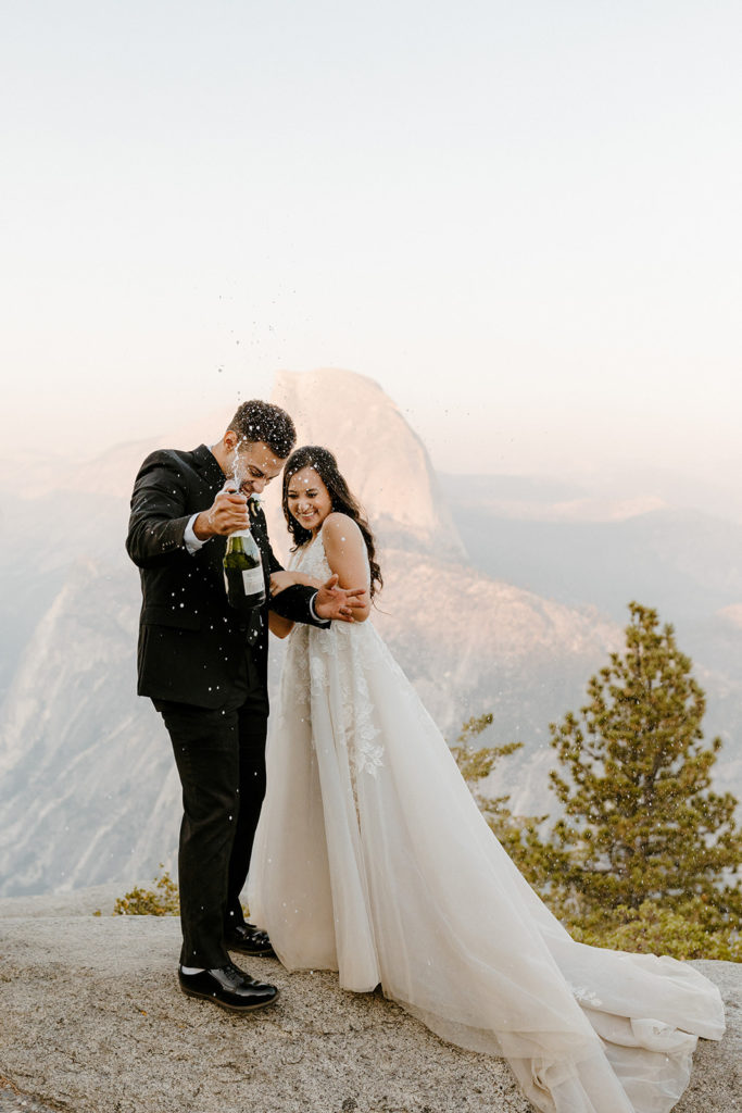 rachelchristophersonphotos-glacier point yosemite elopement-yosemite elopement-glacier point elopement-mountain top elopement-northern california elopement-bride and groom-slick black suit-lacey floral wedding gown-champagne pop-champagne pop photos