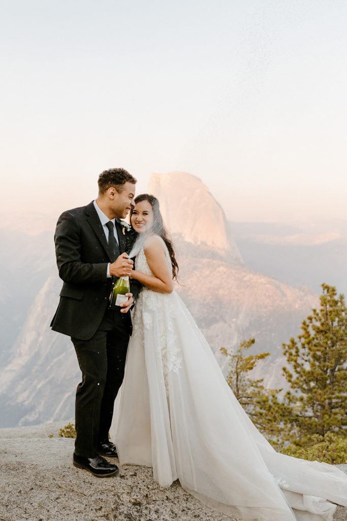 rachelchristophersonphotos-glacier point yosemite elopement-yosemite elopement-glacier point elopement-mountain top elopement-northern california elopement-bride and groom-slick black suit-lacey floral wedding gown-champagne pop-champagne pop photos