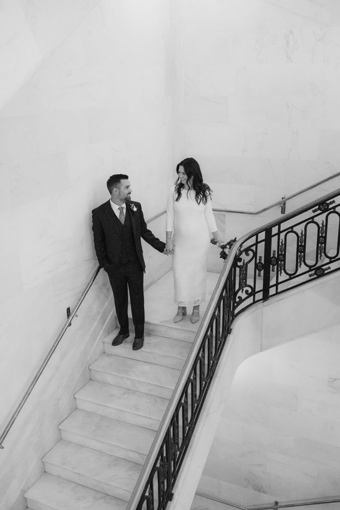 Rachel Christopherson Photographer-SF, San Francisco city hall elopement, san francisco wedding, bride and groom walking down stairs, candid wedding portraits, black and white