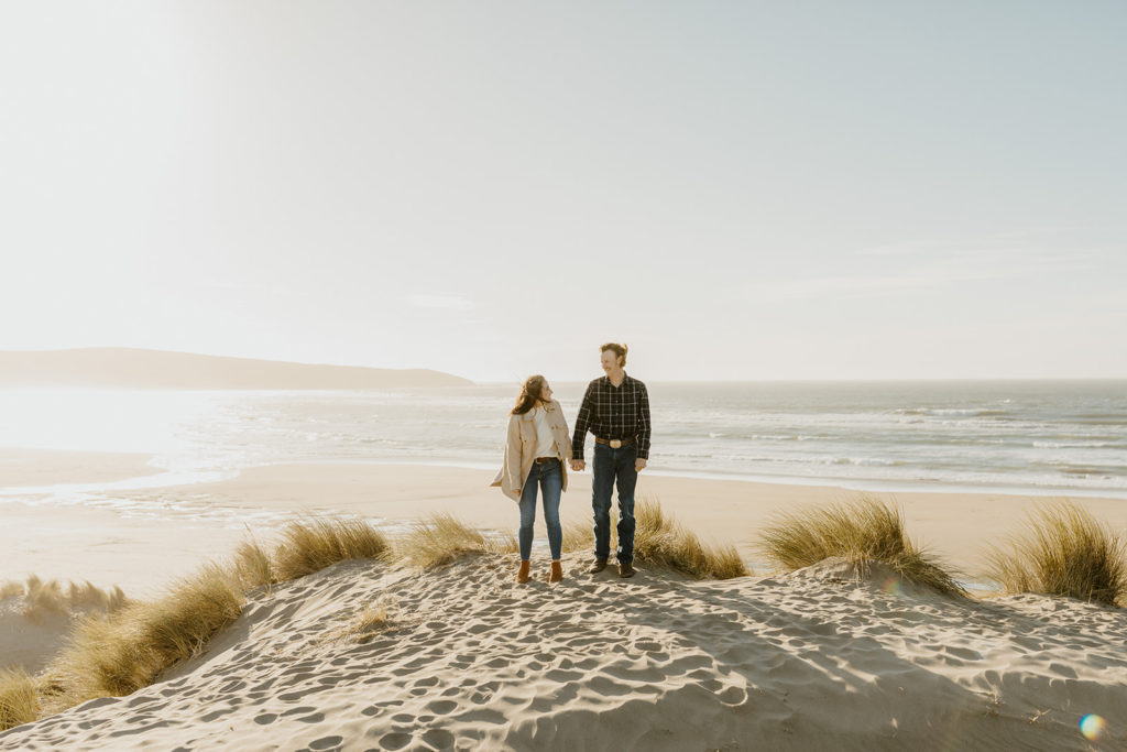 Rachel Christopherson Engagement Photographer-Engaged couple holding hands and smiling at each other on beach-San Francisco Engagement Photos, Northern California Engagement Photos, Point Reyes Engagement Photos, Bodega Bay Engagement Photos, Dillon Beach Engagement Photos, Bay Area Engagement Photos