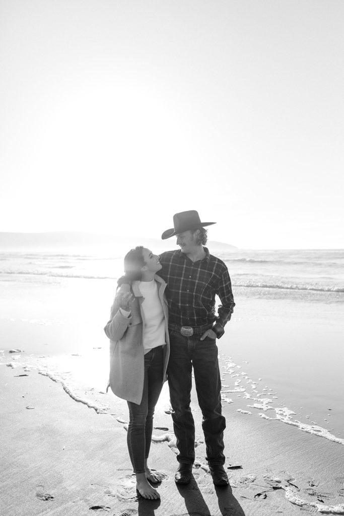 Rachel Christopherson Engagement Photographer-Engaged couple holding hands and smiling at each other on beach, black and white engagement photos-San Francisco Engagement Photos, Northern California Engagement Photos, Point Reyes Engagement Photos, Bodega Bay Engagement Photos, Dillon Beach Engagement Photos, Bay Area Engagement Photos