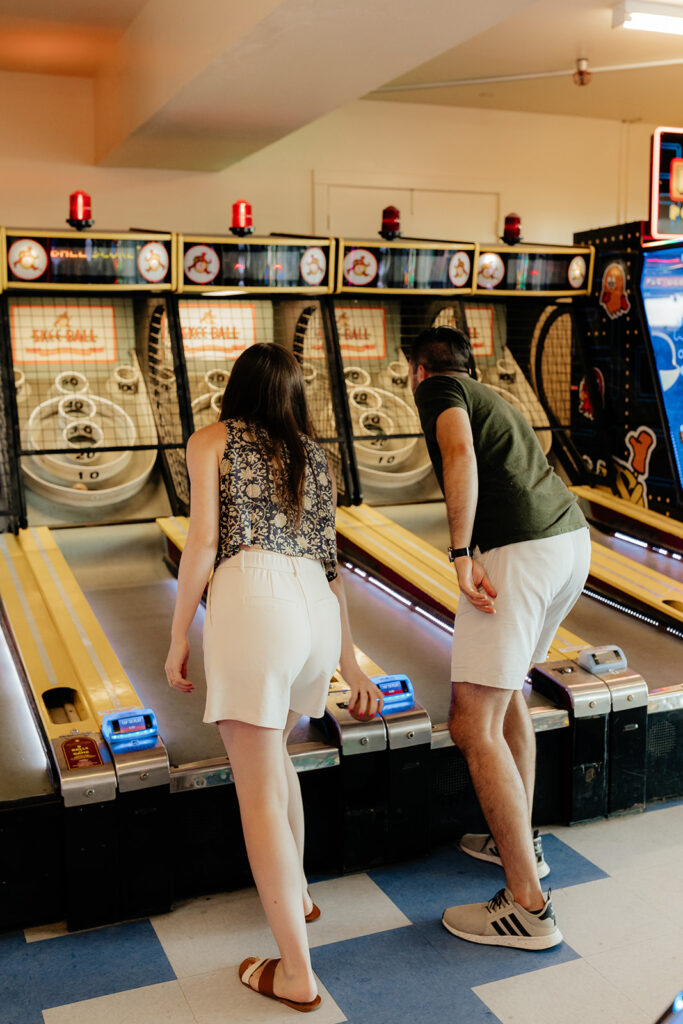 Couple playing skee ball at an arcade