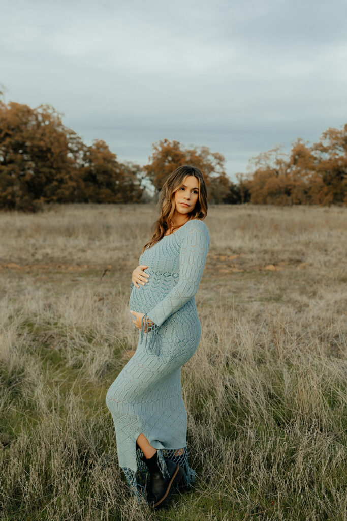 Pregnant woman posing for photos in an open field