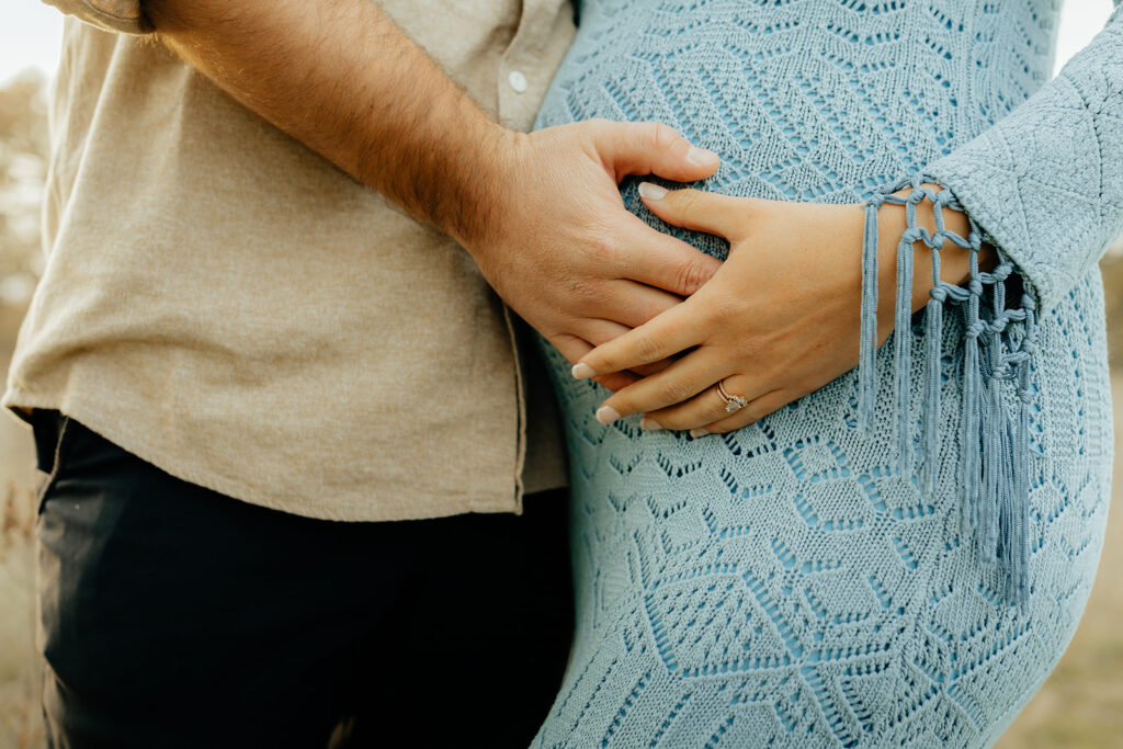 Man and woman holding womans pregnant belly