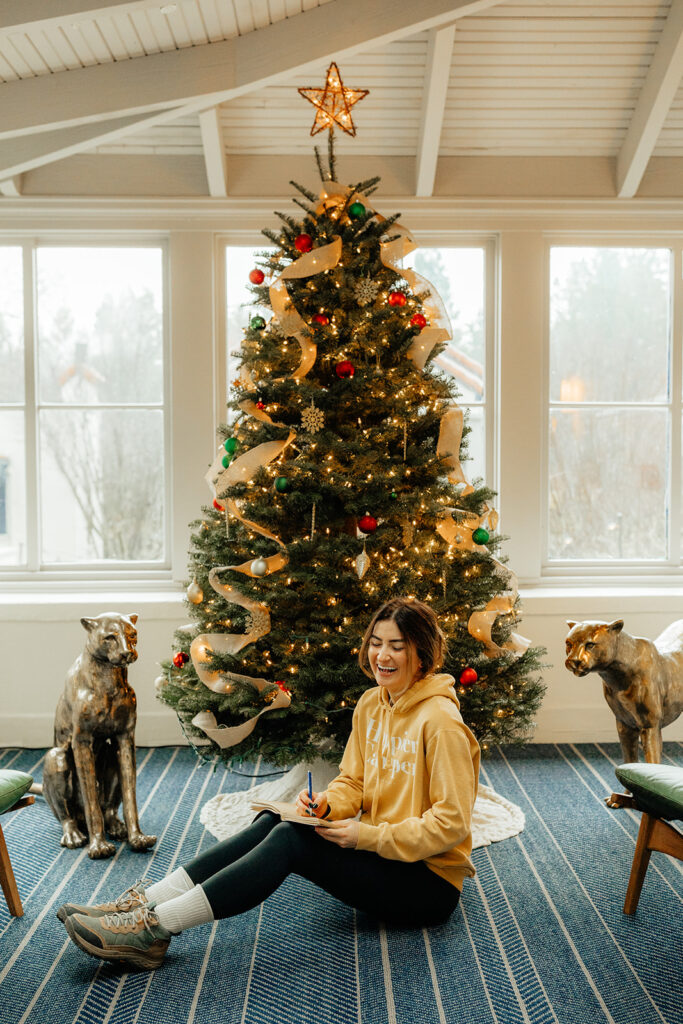 Woman writing in front of a Christmas tree