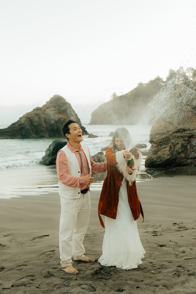 Bride and groom popping champagne on the beach