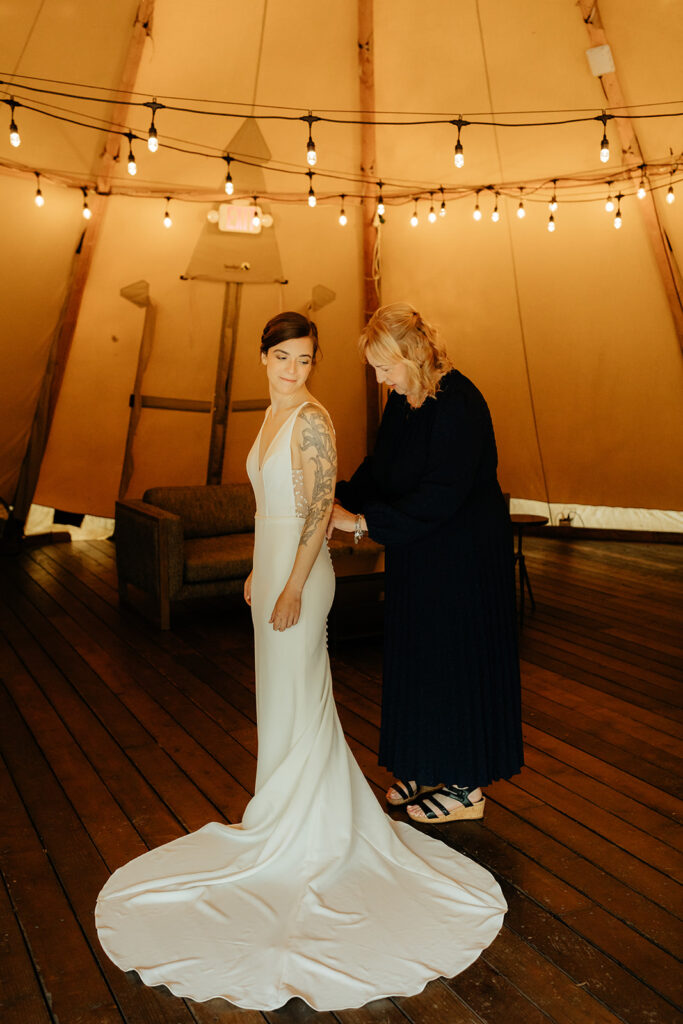 mother of the bride helping her with her wedding dress 