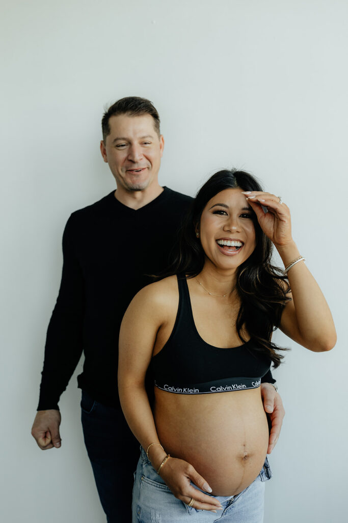 couple laughing at at the camera during their maternity session