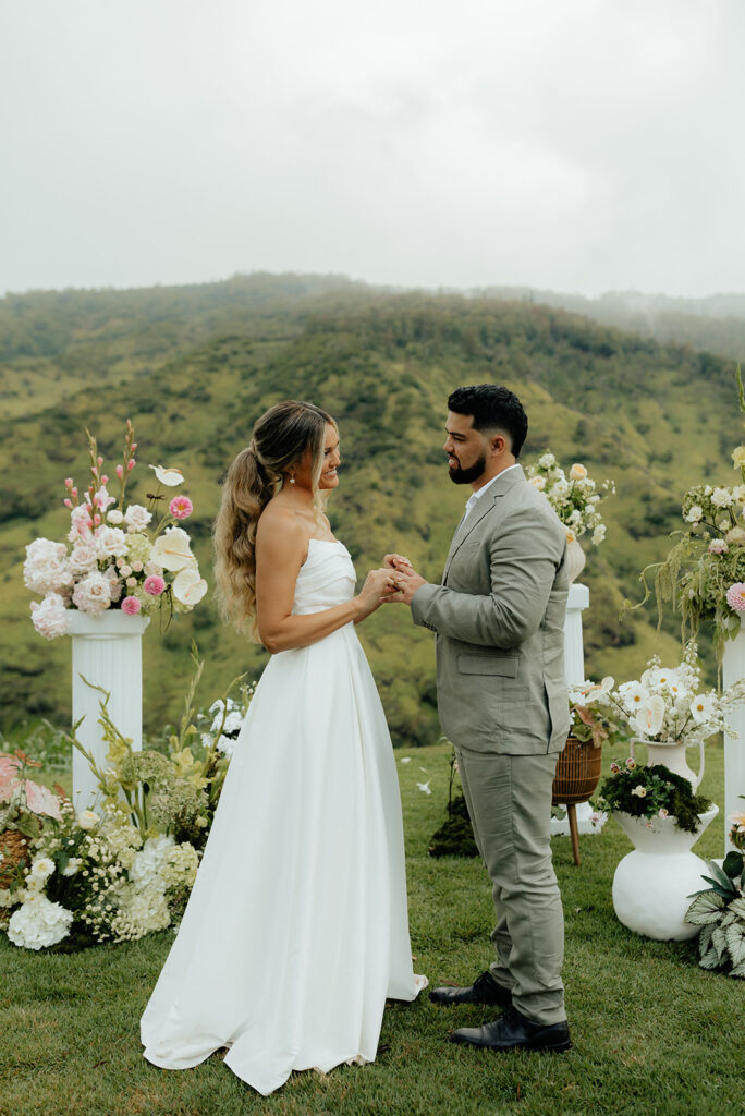 bride and groom holding hands looking at each other during their wedding ceremony 