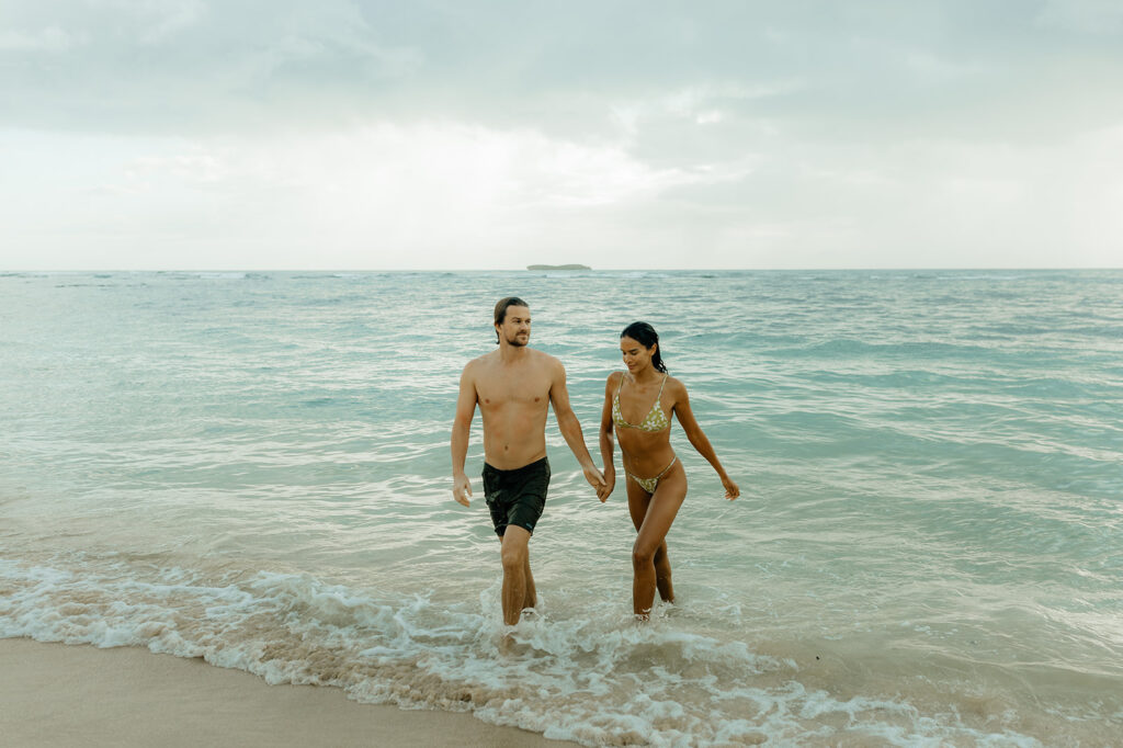 cute couple holding hands walking around the beach 